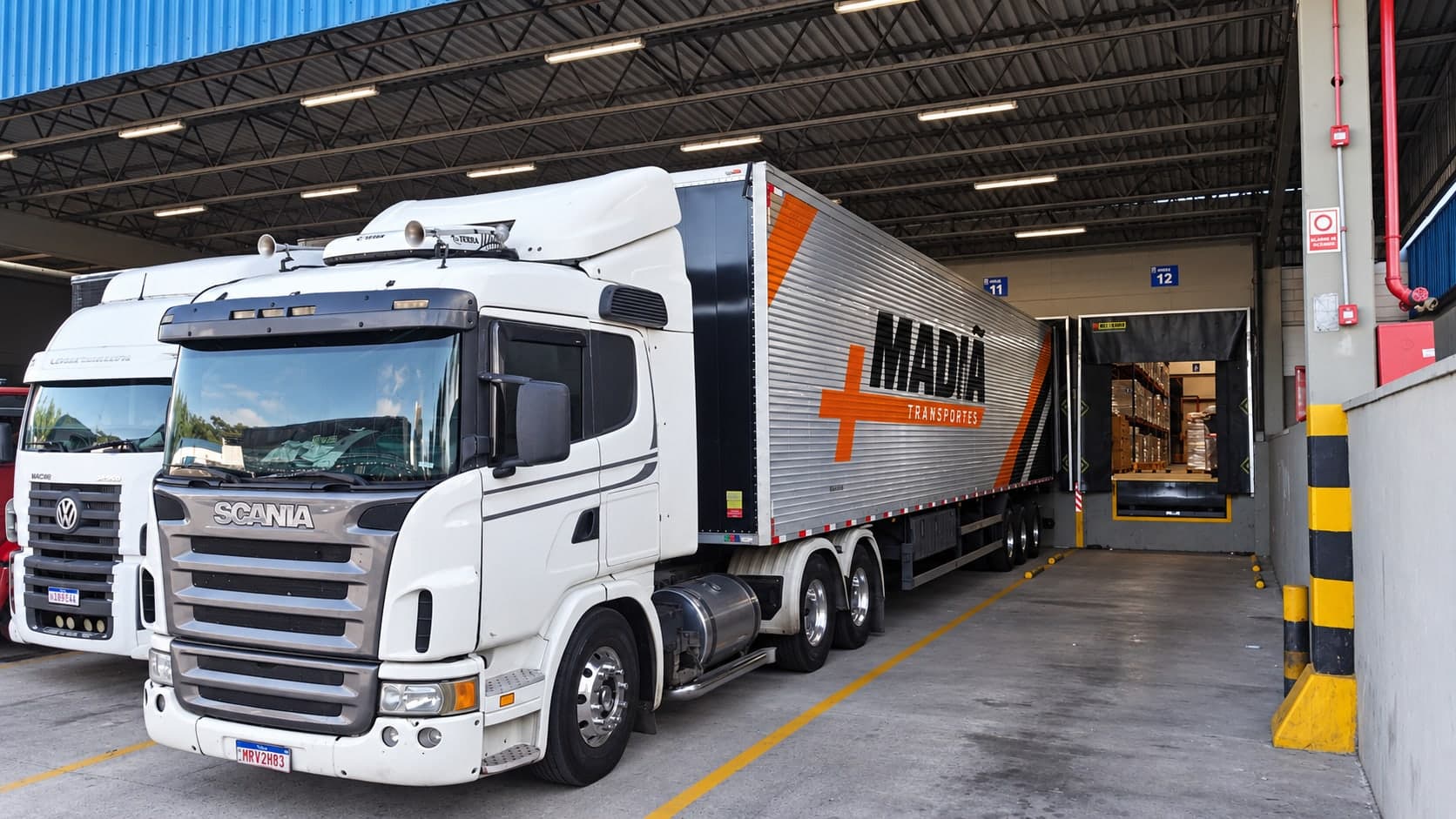 Carreta baú da Madiã Transportes encostada na doca de um galpão